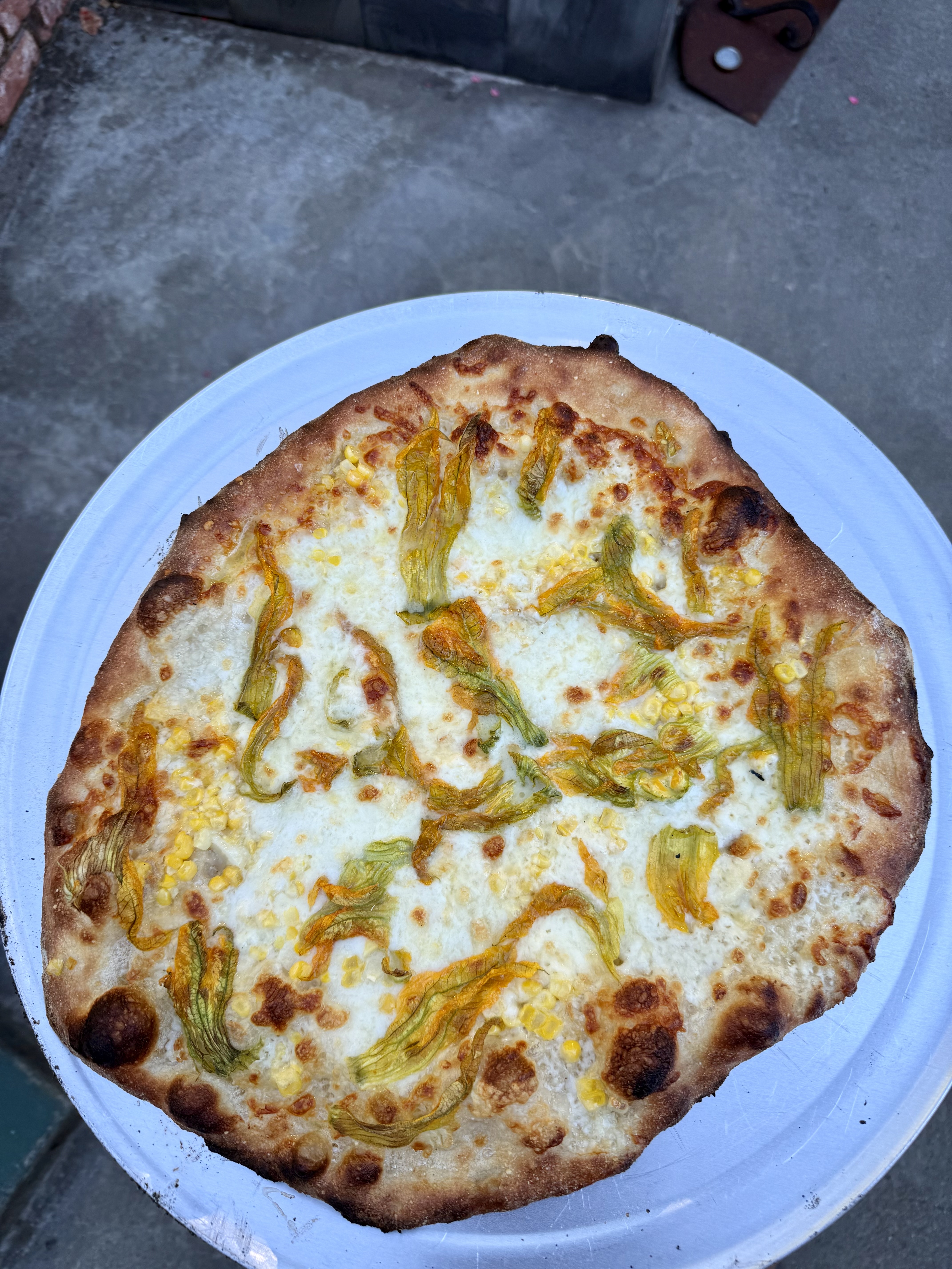 Squash blossom and corn pizza baked New Haven–style, with a thin charred crust