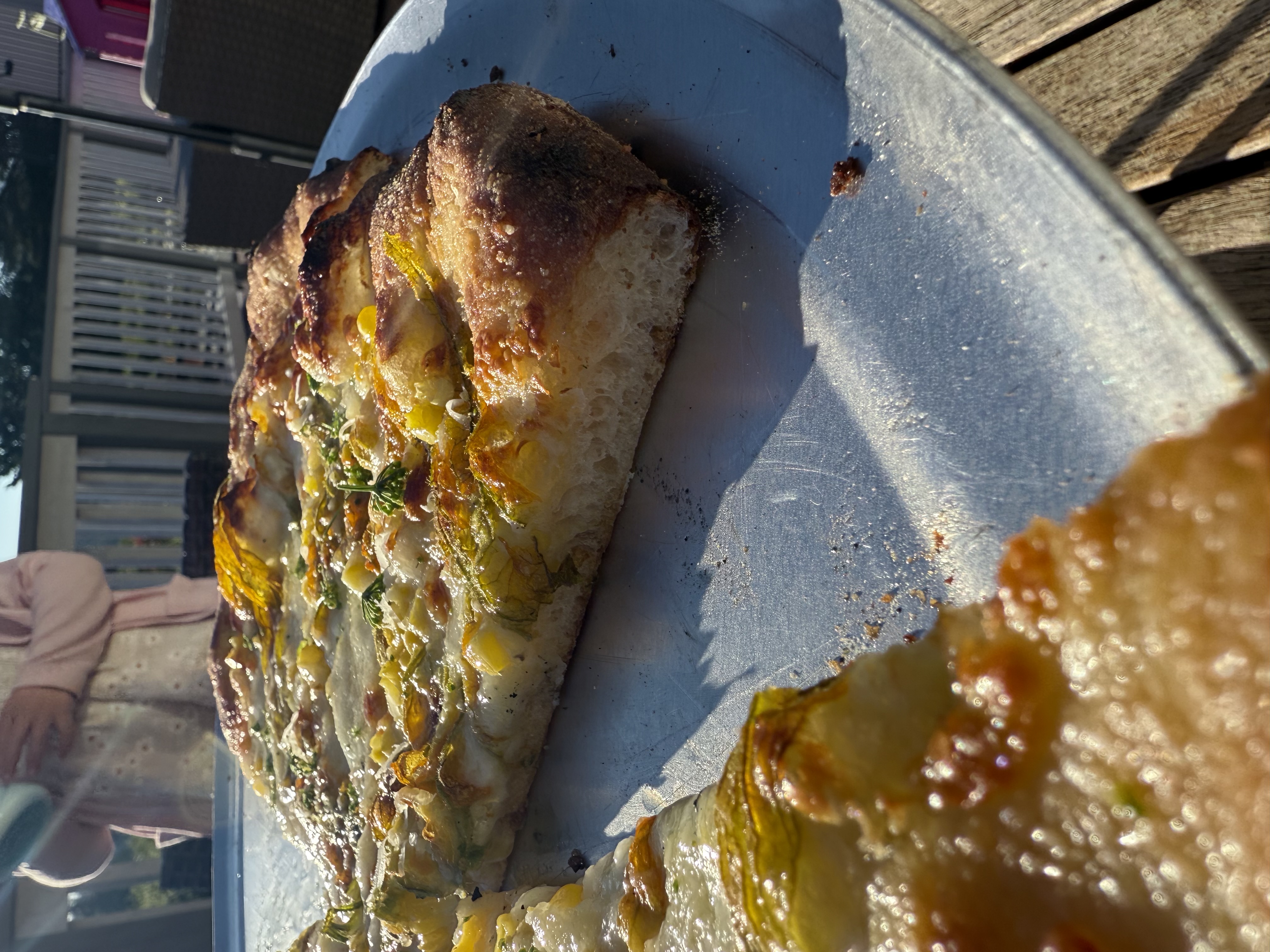 A slice of New Haven–style pizza being held up, showing the thin crisp undercarriage