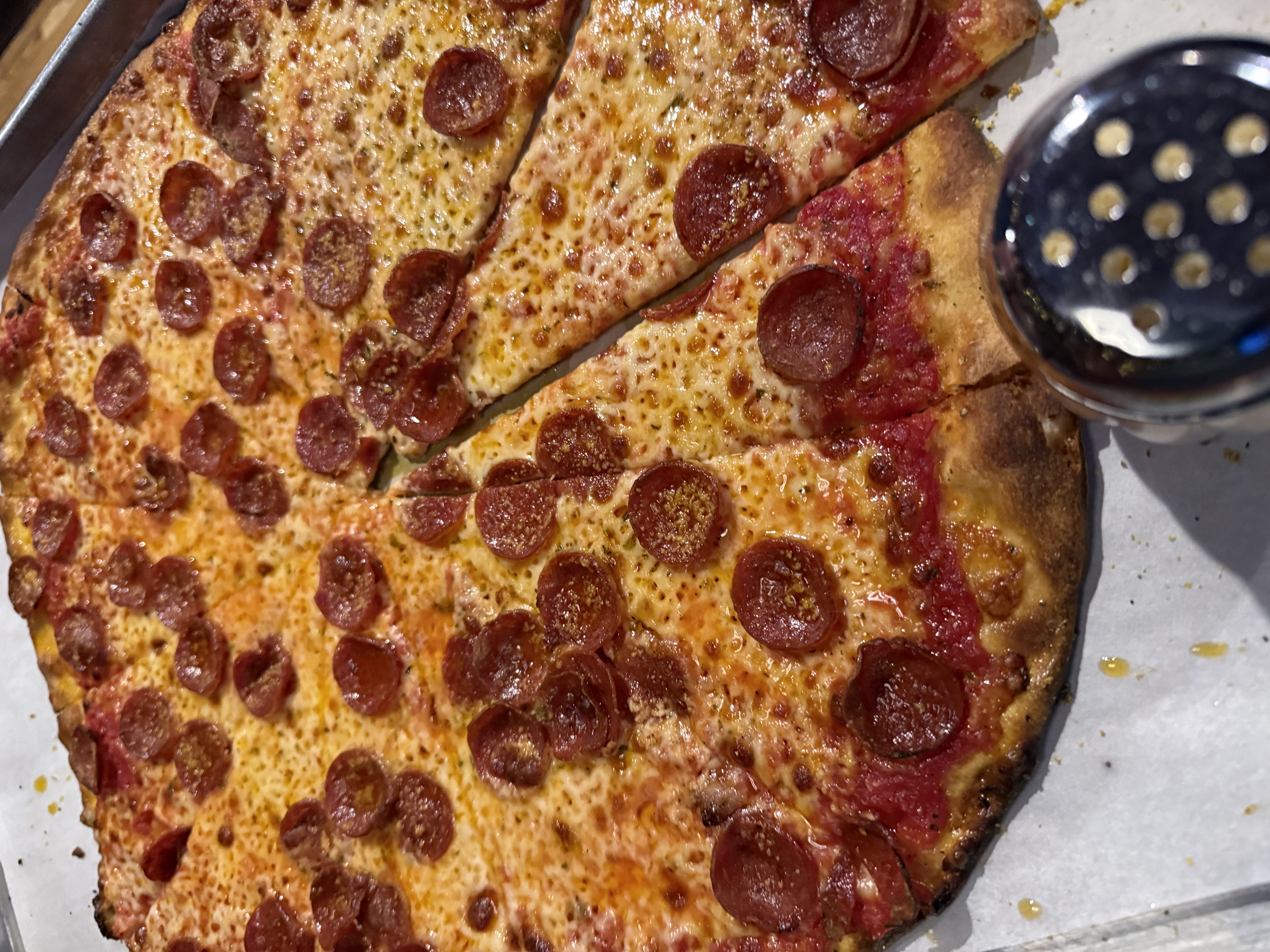 Pepperoni pizza at Piece Pizzeria in Chicago, cut into uneven pieces on a metal tray