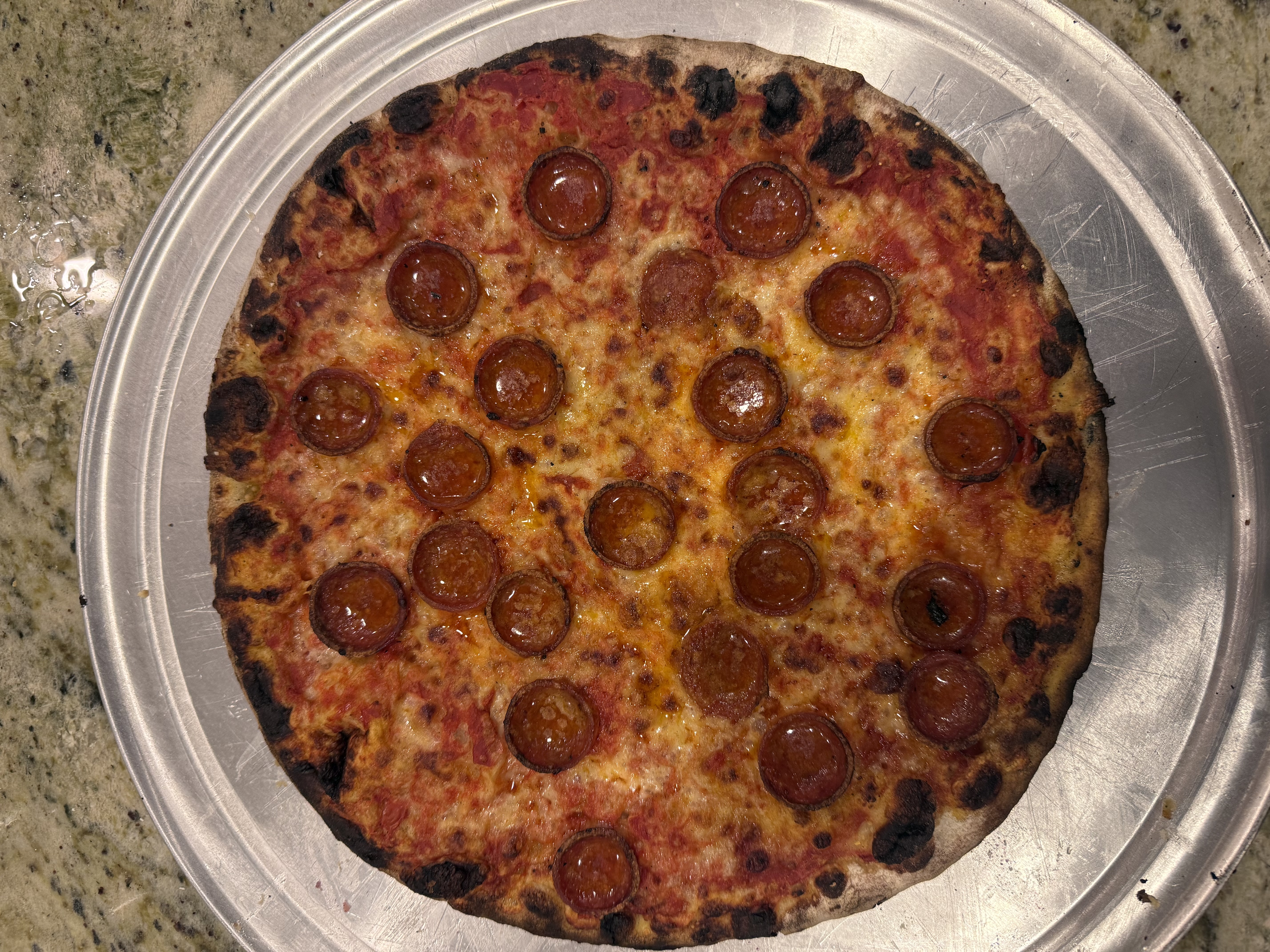 Whole pepperoni apizza from Sally's Apizza in New Haven, with a blistered, charred edge on a metal pan